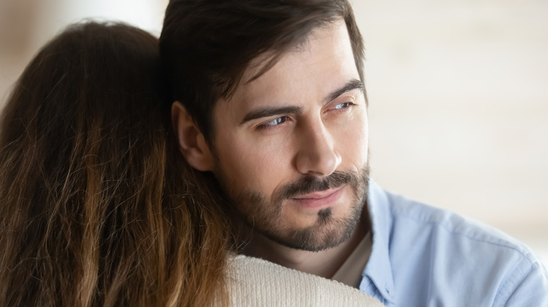 Man looking deceptively over woman's shoulder