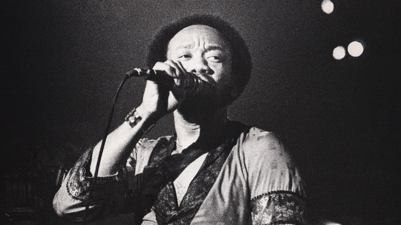 Maurice White singing on stage spotlit 
