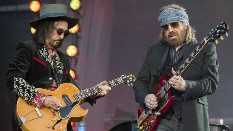 Mike Campbell and Tom Petty playing guitars on stage