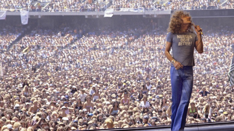 Robert Plant sings on stage in front of a giant crowd