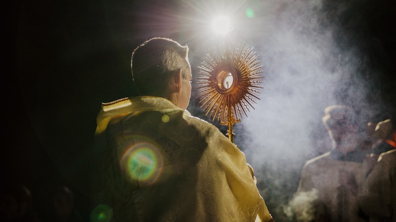 Catholic priest holding Eucharist incense smoke
