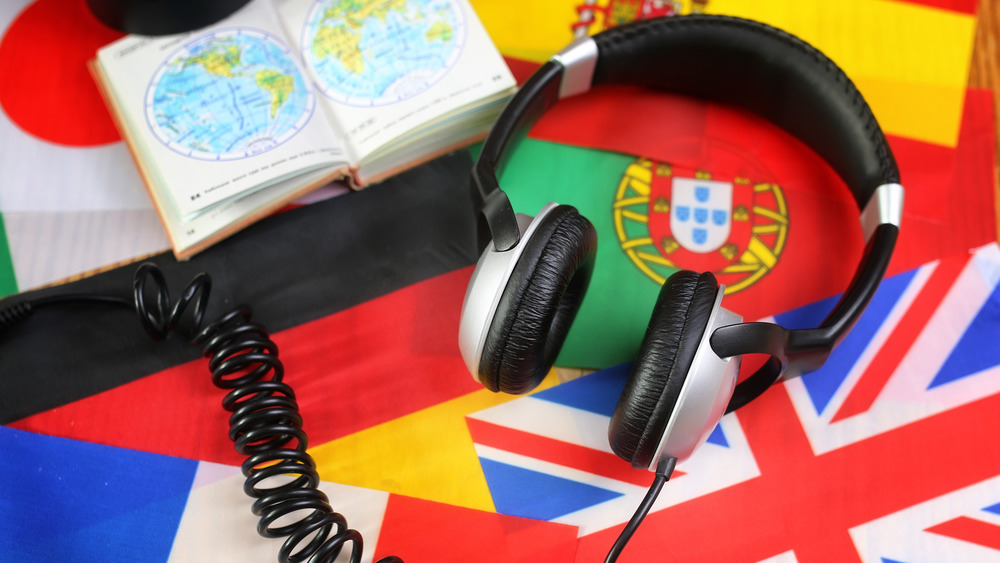A photograph of headphones on top of a variety of world flags.