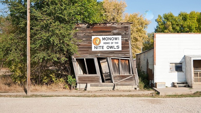 Old rickety wood shack by trees and Monowi sign