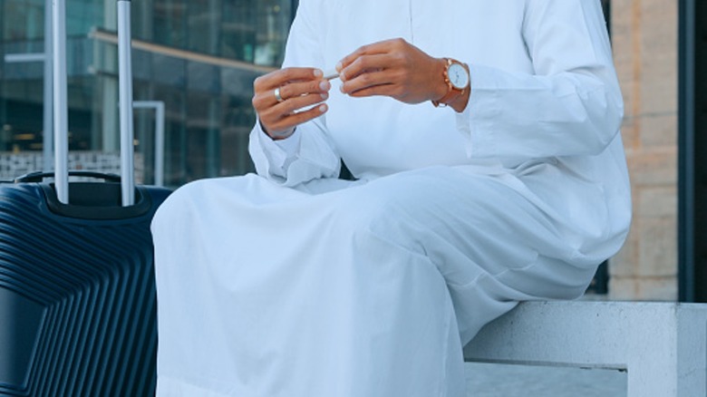 Man in thawb holding joint