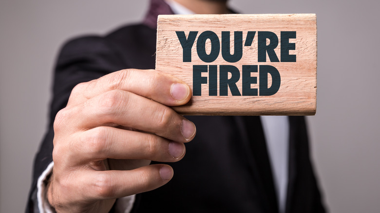 Man holding 'you're fired' sign