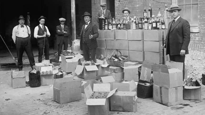 Prohibition agents stand with boxes and bottles of wine and liquor 