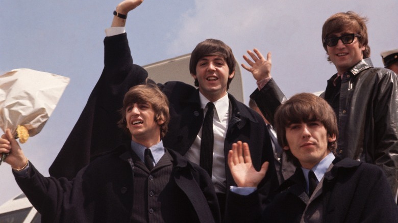 Beatles waving beside plane