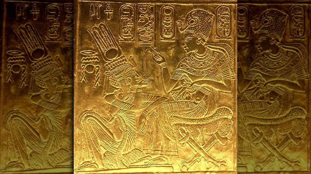 Scene from the golden shrine of Tutankhamun. King and Queen are seated and Tutankhamun seems to pour ointment on Queen's hand.