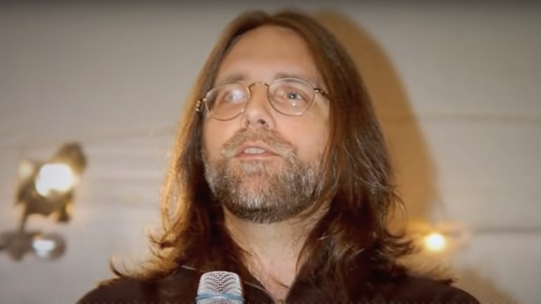 Keith Raniere with long hair and microphone