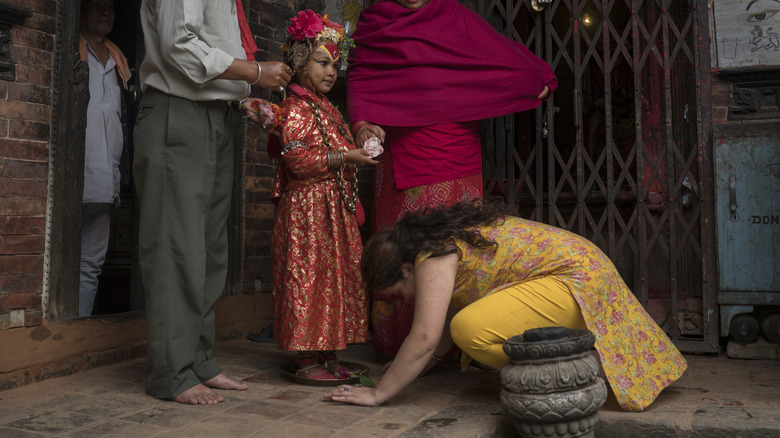 woman kneels down to worship Jibika Bajracharya, the newly appointed child goddess Kumari, in the Sakotha temple on October 7, 2016 in Bhaktapur, Nepal