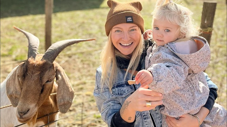 Mandy Hansen holding her daughter near a goat