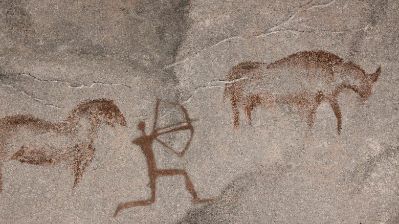 Cave drawing of person hunting animals
