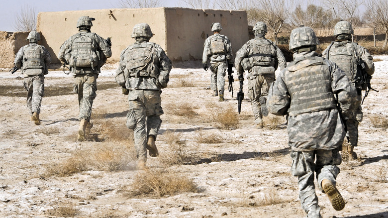 U.S. soldiers running towards building, Afghanistan