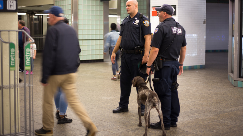 NYPD officers talking with dog in subway station