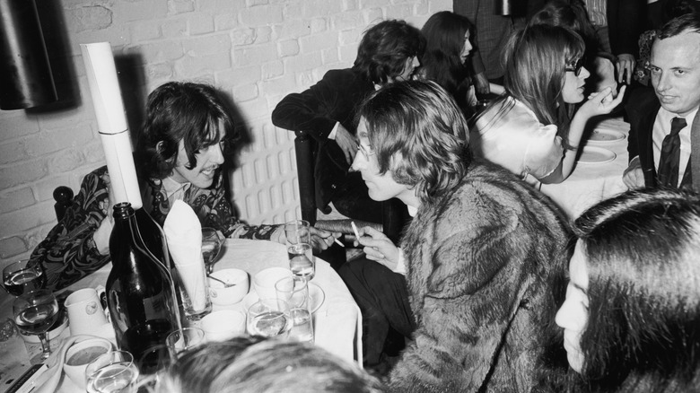 George Harrison and John Lennon sitting at table talking