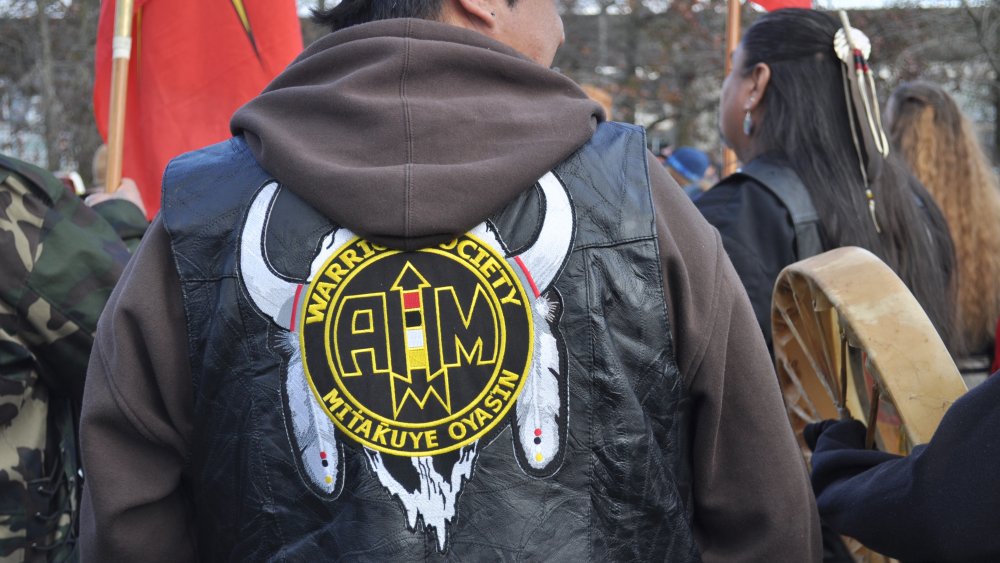  A member of the Warrior Society Mitakuye Oyasin wears an AIM jacket at the raising of the John T. Williams Memorial Totem Pole, Seattle Center, 2015