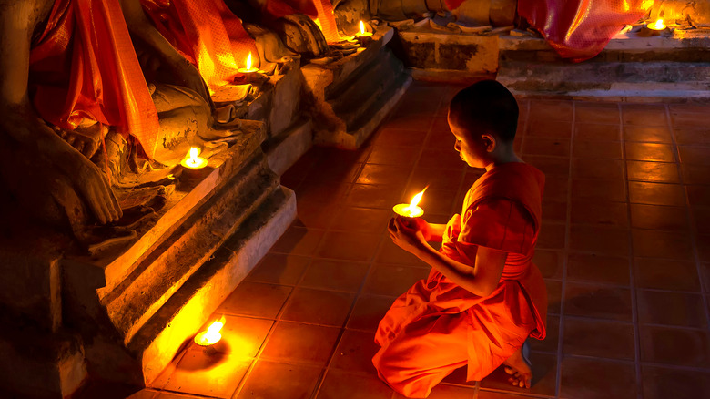 Young Buddhist monk holding a candle