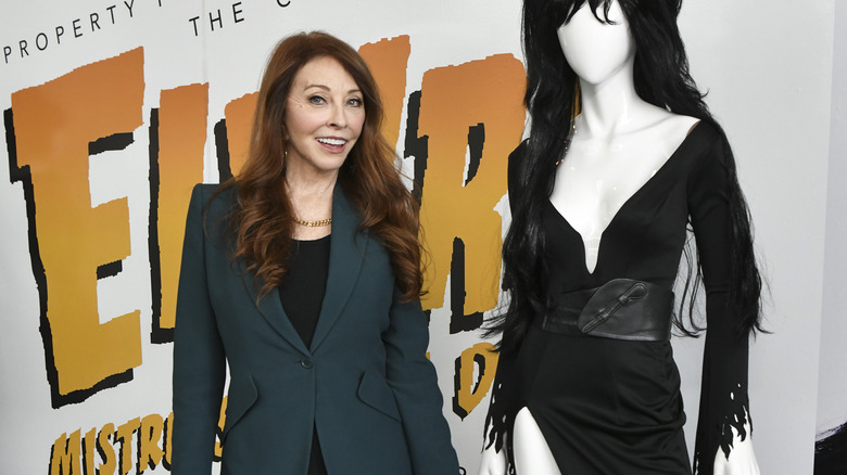 Cassandra Peterson standing next to her Elvira costume